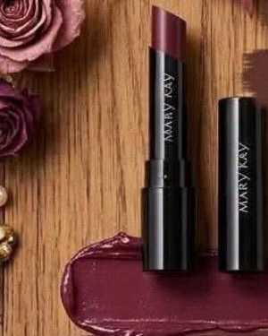 Plum satin lipstick standing next to its cap above a matching swatch